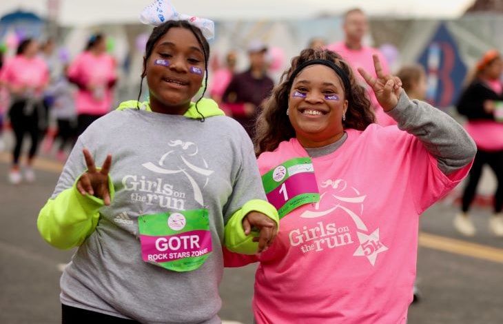 A GOTR girl and her Running Buddy smiling at the camera as the participate in the 5K